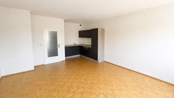 Heller Wohnbereich mit Parkettboden und integrierter Küchenzeile, ideal für offenes Wohnen.