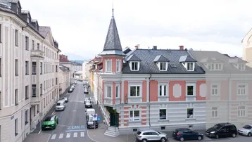 Historisches Eckgebäude mit markantem Turm und umliegender Stadtansicht.