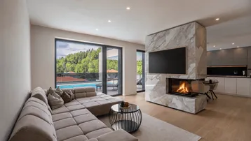 Offener Wohnbereich mit modernem Kamin, bequemer Couch und Blick auf den Pool.