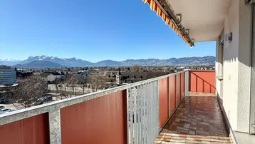 Heller Balkon mit Markise, Fliesenboden und weitem Blick auf die Berge und die Stadt.