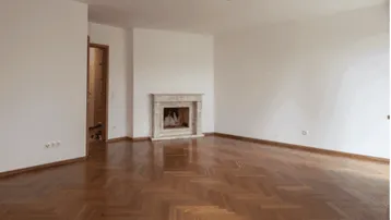 Geräumiges Wohnzimmer mit klassischem Marmorkamin und glänzendem Fischgrätparkett.