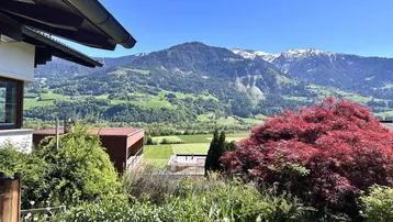 Malerischer Ausblick auf grüne Berge und schneebedeckte Gipfel von einem erhöhten Standpunkt.