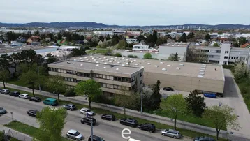 Luftaufnahme eines Gewerbegebiets mit mehreren Gebäuden und Parkplätzen unter bewölktem Himmel.