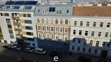Luftaufnahme einer historischen Wohngebäudezeile mit modernen Anbauten und Solarpaneelen auf dem Dach.