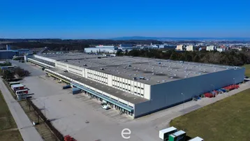 Luftaufnahme eines weitläufigen Industrie- und Lagerkomplexes mit zahlreichen Laderampen unter blauem Himmel.