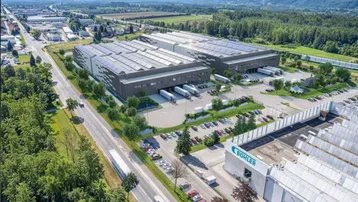 Luftaufnahme eines modernen Industrie- und Logistikkomplexes mit Solaranlagen auf den Dächern und weitläufigen Parkplätzen.