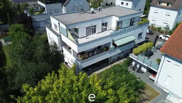 Moderne Wohnanlage mit mehreren Balkonen und Terrassen, umgeben von viel Grün.