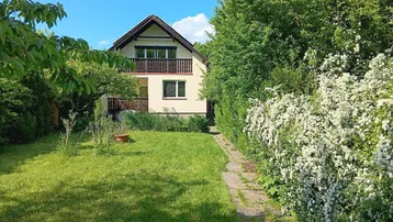 Gepflegter Gartenbereich mit Rasenfläche und einem charmanten Haus im Hintergrund, umgeben von üppigem Grün.