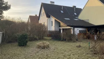 Hinteransicht des Hauses mit Gartenbereich und kahlen Sträuchern in der Übergangszeit.