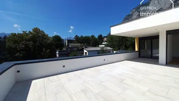 Geräumige Terrasse mit hellen Fliesen und weitem Blick auf die umliegende Berglandschaft.