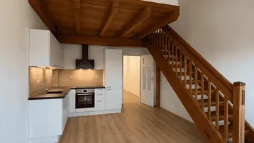 Heller Wohnbereich mit integrierter Küche, Holztreppe und Galerie, ideal für modernes Wohnen.