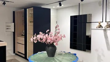 Moderner Innenraum mit stilvoller Einrichtung, schwarzen Schränken und einem dekorativen Tisch mit Blumen.