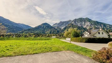 Modernes Gebäude in ländlicher Umgebung mit weiten Feldern und majestätischem Alpenpanorama.