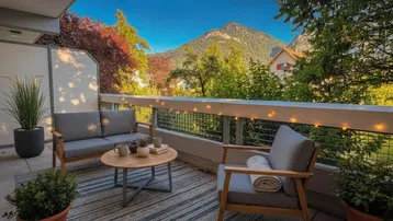 Gemütlicher Balkon mit Sitzgelegenheiten und herrlichem Bergblick unter blauem Himmel.