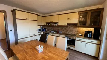 Einbauküche mit beigen Schränken, Esstisch und Laminatboden, ideal für gemeinsame Mahlzeiten.