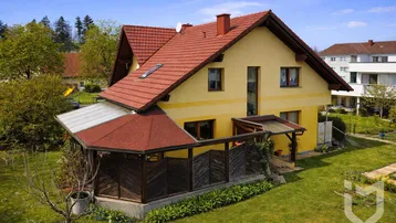 Luftaufnahme eines gepflegten gelben Hauses mit rotem Ziegeldach und weitläufigem grünen Garten.