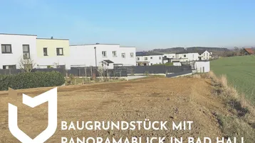 Baugrundstück mit Panoramablick, umgeben von Neubauten und grünen Feldern unter blauem Himmel.