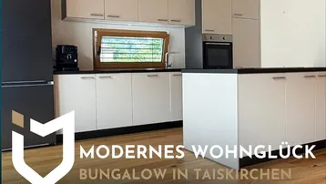 Moderne Küche mit weißen Schränken, dunkler Arbeitsplatte und Holzboden, inklusive Einbaugeräten.