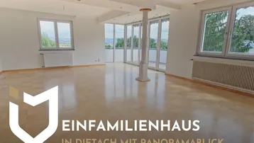 Geräumiger, heller Wohnbereich mit Holzboden, großen Fenstern und Zugang zu einem Balkon mit Panoramablick.