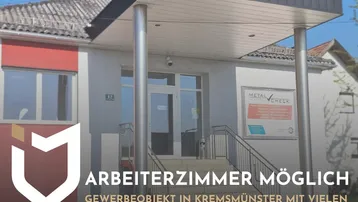 Vorderansicht eines Gewerbeobjekts mit Eingangsbereich und Vordach, teilweise verdeckt durch Werbebanner.