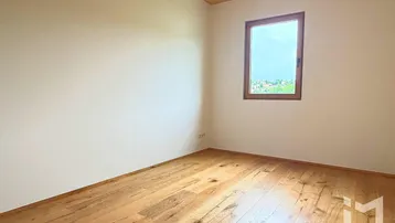 Helles Zimmer mit Holzboden und Holzdecke, bietet einen weiten Blick über die umliegende Landschaft.