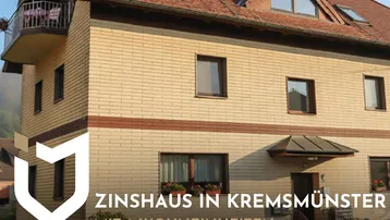Mehrfamilienhaus mit Ziegeldach und Balkon in Kremesmünster, mit Werbebanner.