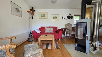 Wohnzimmer mit rotem Sofa, Holzboden und einem modernen Holzofen für gemütliche Abende.