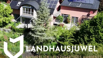 Luftaufnahme eines Landhauses mit Solaranlagen, umgeben von üppiger Natur und einem Teich.