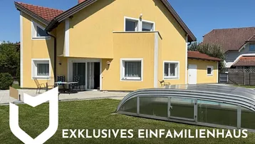 Exklusives Einfamilienhaus mit Pool und Garten, umgeben von Natur, unter blauem Himmel.