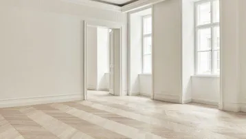 Heller, leerer Raum mit elegantem Fischgrätparkett, hohen Decken und großen Fenstern, der vielseitig nutzbar ist.