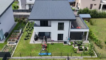 Übersicht des modernen Einfamilienhauses mit Garten, Terrasse und Kinderspielplatz aus der Vogelperspektive.