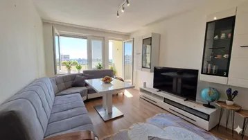 Helles Wohnzimmer mit modernem Sofa, TV-Möbeln und direktem Zugang zum sonnigen Balkon.