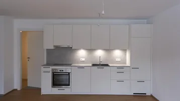 Moderne Einbauküche in Weiß mit integrierten Geräten und hellem Holzfußboden.