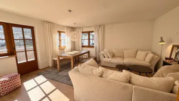 Helles Wohn- und Esszimmer mit bequemen Sofas, Holztisch und viel natürlichem Licht.