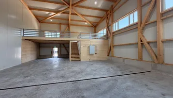 Geräumige Lagerhalle mit hohen Decken, sichtbaren Holzbalken und einer Holzempore.