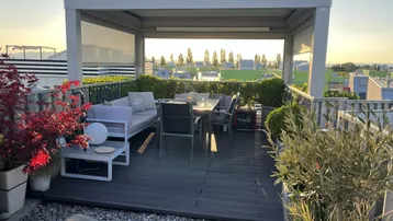 Geräumige Dachterrasse mit gemütlichen Loungemöbeln, Essbereich und Pergola, ideal für entspannte Abende.