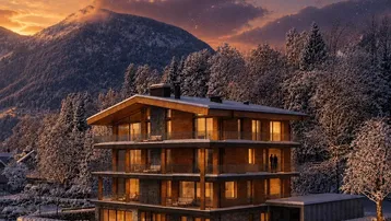 Modernes Mehrfamilienhaus mit Holz- und Steinfassade in verschneiter Berglandschaft bei Sonnenuntergang.