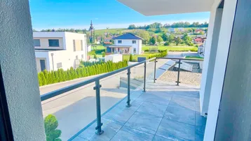 Geräumiger Balkon mit Fliesenboden und Glasgeländer, bietet einen weiten Blick über die Landschaft.