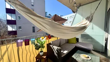 Geräumiger Balkon mit Hängematte, Sitzgelegenheiten und Blick auf die umliegenden Gebäude.