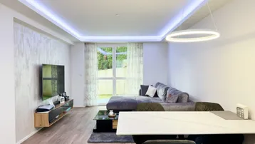 Lichtdurchfluteter Wohn-Essbereich mit Zugang zum Garten, modernem Sofa und dekorativer Wandgestaltung.