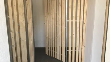Innenraum mit Holzlattenabtrennungen, die als individuelle Lagerräume dienen und einen funktionalen Kellerbereich schaffen.