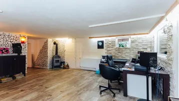 Ausgebauter Kellerraum mit Laminatboden, Kaminofen und einer Arbeitsfläche für kreative Projekte.