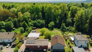 Luftaufnahme der Liegenschaft mit umliegenden Häusern, Wald und einem Pool im Gartenbereich.