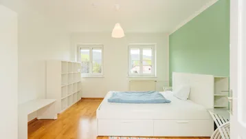Helles Schlafzimmer mit Holzboden, einem Bett mit Stauraum und einer mintgrünen Akzentwand.