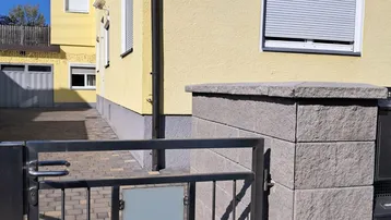 Gebäudeansicht mit Eingangstor und Hausnummer 91 unter blauem Himmel.
