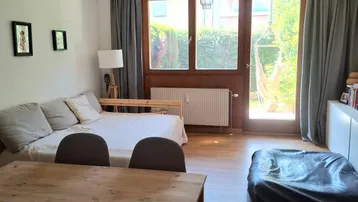 Heller Wohn- und Essbereich mit Holzboden und direktem Zugang zum grünen Garten.