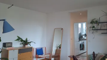 Helles Wohnzimmer mit Holzboden, modernen Möbeln und Blick in die offene Küche.