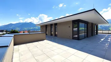 Große Dachterrasse mit modernen Fliesen und weitem Blick auf die umliegende Berglandschaft.