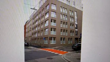 Modernes Wohnhaus mit mehreren Etagen und großen Fenstern an einer Stadtstraße.