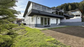 Moderne Wohnanlage mit Balkonen und Gartenbereich in sonniger Hanglage.